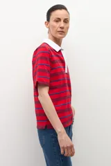 Remera de manga corta con cuello polo blanco y escote pronunciado en V. El cuerpo de la prenda es de color rojo con finas rayas horizontales en azul oscuro y azul claro.