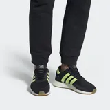 Zapatillas Adidas I-5923 negras con detalles en amarillo neón y suela blanca con base color caramelo.
