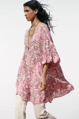 Vestido corto con estampado floral en tonos rosados, escote en pico y mangas abullonadas.