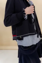 Saco tejido color negro con detalle en escote y puños a dos tonos, corte acampanado y detalle en la espalda con cambio de punto y color.