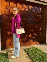 Cartera bandolera de cuero crudo con forro de tela, bolsillo frontal y bolsillo interno. Tiene correa larga regulable y manijas cortas de cuero marrón.