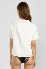 Camisa color crema de lino y tencel, de manga corta, con cuello camisero y cierre abotonado al frente.