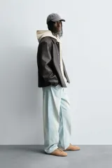 Cazadora de efecto piel color marrón oscuro, corte relajado, con cuello solapa, cierre frontal de botones a presión y bolsillos de vivo en cadera.