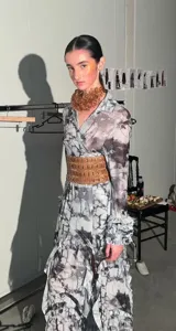 Camisa larga de tul elastizado con cuello solapa, abotonada y con volados en las mangas. Estampado abstracto en tonos grises y negros. Incluye cinturón ancho color marrón con detalles calados.