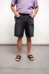 Bermuda de jean negra con roturas y largo a la rodilla.