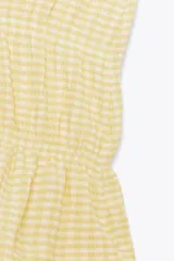 Top amarillo con estampado de cuadros vichy blancos, escote en pico, sin mangas, con detalle de elásticos en la cintura y cierre frontal con lazadas.