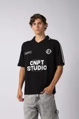 Remera tejida color crudo con cuello tipo chomba en V, mangas cortas con rayas negras y estampado con letras en el frente. Confeccionada en hilado de algodón.