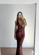 Vestido largo de microtul con estampado abstracto en tonos marrones, azules y naranjas. Tiene escote en V con encaje negro y breteles finos.