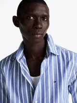 Camisa de popelín de algodón a rayas verticales azules y blancas, de corte regular, con cuello abotonado, puños redondeados con botón y logo de Tommy Hilfiger bordado en el pecho.