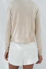 Jersey color crema de punto liso con cuello redondo y manga larga, confeccionado con lana.