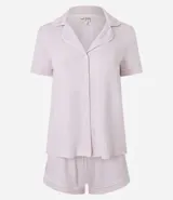 Conjunto de pijama americano compuesto por una blusa de manga corta con cuello solapa y abotonado frontal, y un short con cintura elástica y lazo. El conjunto es liso en color rosa pálido, con vivos contrastantes en el borde de las prendas.