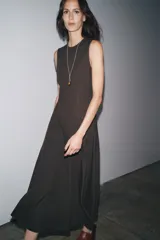 Vestido midi marrón sin mangas confeccionado en hilatura con 10% de lino. Tiene cuello redondo, corte evasé y cierre trasero con cremallera oculta.