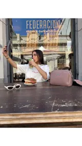 Bandolera pequeña de textura símil cuero color caramelo/marrón, con dos compartimentos principales con cierre. Correa ancha ajustable de tela negra con inscripción en relieve.