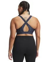 Top deportivo Under Armour con estampado floral en tonos rosa y amarillo sobre fondo negro. Cuenta con tirantes cruzados en la espalda y banda elástica con el logo de la marca en el contorno inferior.