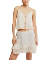 Top blanco con tirantes finos y escote en V, con detalle de bordado delicado en los bordes y abertura frontal con botones.