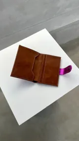 Porta pasaporte marrón con apliques plateados y cierre con broche.