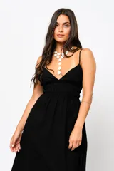 Vestido largo negro con escote en V, tirantes finos y espalda baja. Tiene frunces en la cintura que realzan la silueta.
