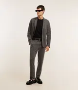 Pantalón de vestir gris con textura, corte slim, con trabillas en la cintura y cierre por botón y cremallera.