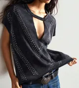 Remera negra con cuello redondo y abertura en forma de gota en el escote. Decorada con apliques metálicos en forma de V.