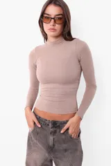 Top manga larga color arena, de media polera y calce slim fit.