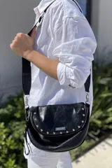 Bandolera negra de cuero vacuno con correa regulable de cinta, forrada en tela de algodón, cierre central y bolsillo con cierre atrás.