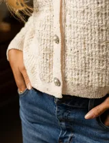 Cardigan de tejido tweed color blanco, marca Catherine Malandrino. Tiene cuello a la base, abertura central con botones perlados, bolsillos simulados en la delantera y bordados en lurex y lentejuelas.