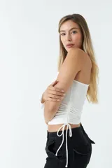 Top asimétrico blanco de una sola manga con jaretas ajustables en ambos lados del torso para regular el largo.