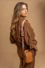 Bandolera pequeña tipo 'phone bag' de símil cuero color rosado pálido, con cierre de cremallera y correa ancha de tela con diseño de chevron en tonos claros.