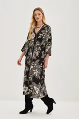 Vestido largo negro con estampado floral en color crema, escote en V y mangas acampanadas.