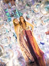 Vestido largo con escote en V, estampado en tonos rojizos y rosados, con un patrón ondulado. Presenta cut-outs laterales bajo el busto y breteles finos que se cruzan en la espalda.