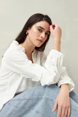 Blusa color amarillo pálido de manga larga con escote en V, mangas abullonadas con volados y botones forrados.