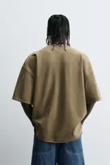 Camiseta color beige de corte holgado, cuello redondo y manga corta.