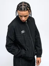 Campera deportiva Umbro color negro, de corte holgado, con cierre frontal y cuello alto. Presenta costuras en contraste de color blanco y logo de la marca bordado en el pecho.
