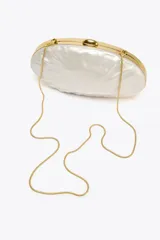 Bolso de mano rígido con forma ovalada irregular y efecto perlado. Tiene laterales metalizados, asa de cadena extraíble y cierre metálico.