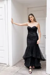 Vestido largo de fiesta color negro con lentejuelas, corte sirena, strapless con escote corazón y falda con volados.