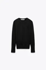 Jersey negro de punto liso con cuello redondo y mangas largas terminadas en puños con botones.