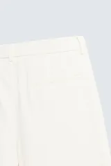 Pantalón de vestir color blanco hueso, de corte recto y tiro medio, con cintura elástica y cierre frontal de botón y cremallera. Presenta bolsillos frontales y bolsillos traseros de vivo.