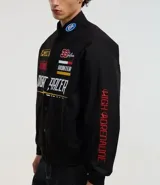 Campera negra con cuello alto, cierre de botones y estampado estilo racing con logos y textos en amarillo, rojo y blanco. Tiene bolsillos laterales y mangas largas con detalles estampados. Marca Blue Steel.