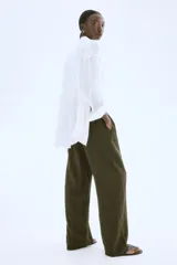 Pantalón verde militar de corte holgado en tejido liviano de mezcla de lino. Modelo de tiro alto con cintura elástica y cordón para ajustar fino, bolsillos laterales discretos y piernas rectas.