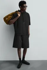 Sudadera negra de algodón con capucha ajustable y mangas cortas.