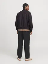 Campera bomber negra de tejido liviano de lino y algodón, con cuello tipo baseball, cierre con cremallera, mangas largas con puños de canalé y bolsillos delanteros.