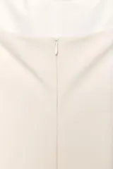 Minivestido blanco con cuello halter, escote recto y falda con volantes y forro tipo short. Presenta cierre con botones en el cuello y cremallera oculta en la espalda.