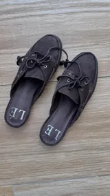 Mules de cuero gamuzado color negro, con detalle de cordones y ojales metálicos.