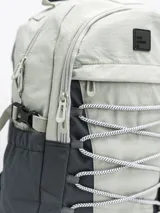 Mochila gris claro y gris oscuro con cordones elásticos cruzados en el frente y logo de la marca en la parte superior.