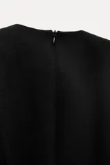 Vestido midi negro de escote pico y manga larga con hombreras. Tiene falsos bolsillos de vivo en el delantero y cierre en la espalda con cremallera oculta.