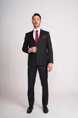 Traje de vestir negro, compuesto por saco de corte clásico con solapa de muesca, dos botones y bolsillo de pañuelo, y pantalón de vestir de corte recto. Incluye camisa blanca, corbata y pañuelo de bolsillo color borgoña, y zapatos de vestir negros.
