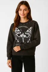 Buzo negro de algodón con cuello redondo y mangas largas. Estampado frontal de mariposa en blanco y negro con texto "The Butterfly" y tachas plateadas en los hombros.