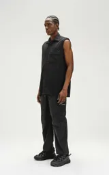 Camisa negra sin mangas de calce oversize con doble bolsillo y detalle de remaches en el frente, confeccionada en tejido twill de alta calidad.