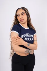 Remera corta de jersey color rosa con cuello redondo y mangas cortas con ribete blanco. Estampado frontal con la inscripción "ST-TROPEZ" en letras blancas.