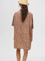 Camisa-vestido oversize de manga corta, color verde con estampado tie-dye en tonos salmón y turquesa. Presenta cuello camisero y cierre frontal de botones.